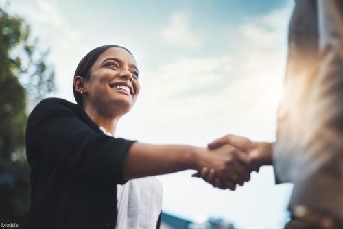 Confident businesswoman outdoors shaking hands with an associate